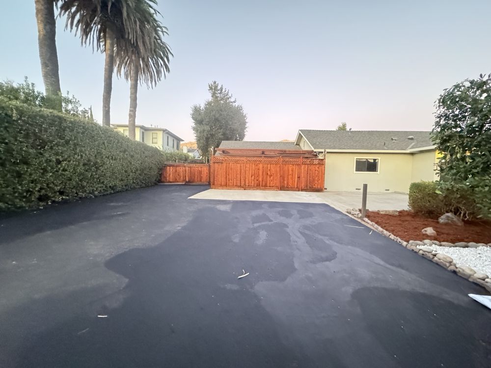 Newly paved drive area at the front of the Milpitas property, meeting fresh concrete flatwork at a redwood fence and gate