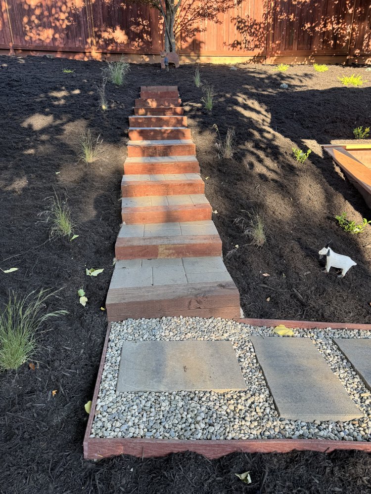 Timber and paver steps climbing the replanted hillside between ornamental grasses and fresh mulch