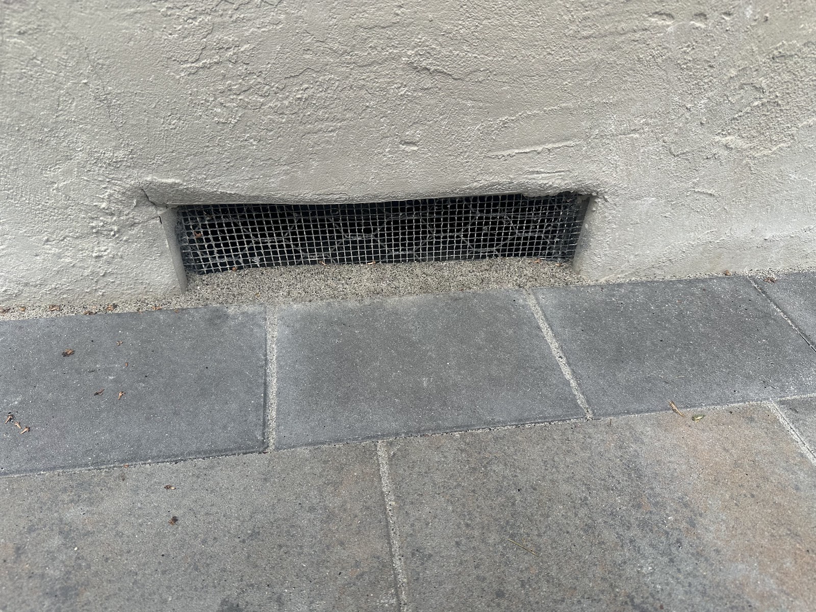 Paver patio laid cleanly up to the house foundation vent