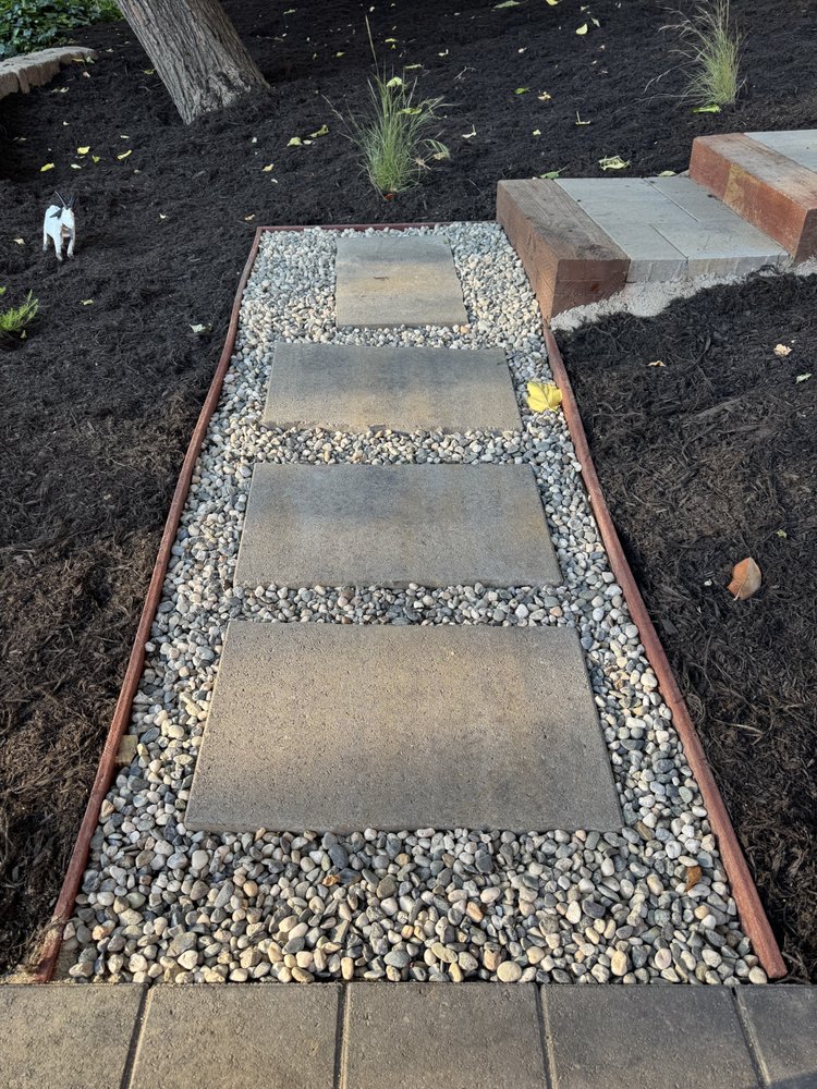 Stepping stone path of square pavers set in rounded gravel with timber edging, crossing the mulched hillside