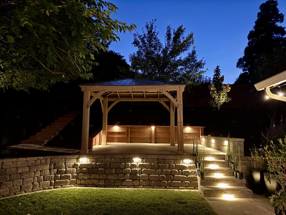 The Walnut Creek patio and gazebo lit at night, with lights washing the block retaining wall and each stone step