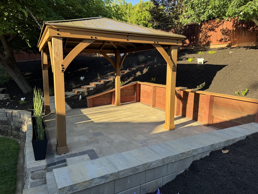Golden-hour photo of the gazebo on the new raised paver patio in Walnut Creek, with the wood retaining wall and bench seat wrapping two sides of the patio
