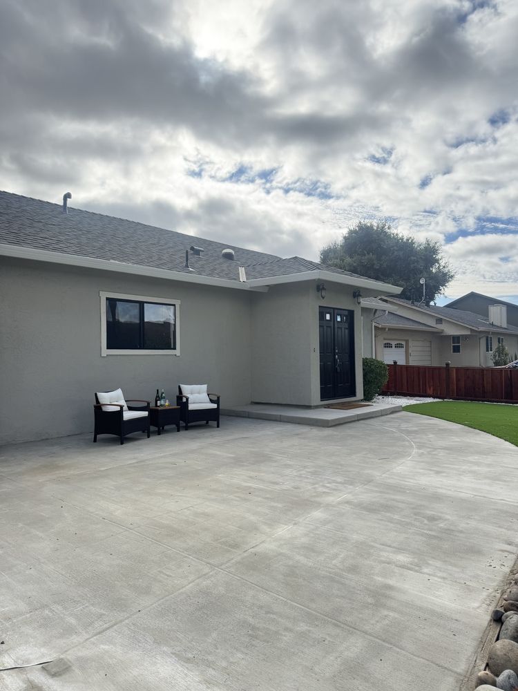 Concrete patio and raised step at the back door of the Milpitas house, with two patio chairs and turf beyond the fence line