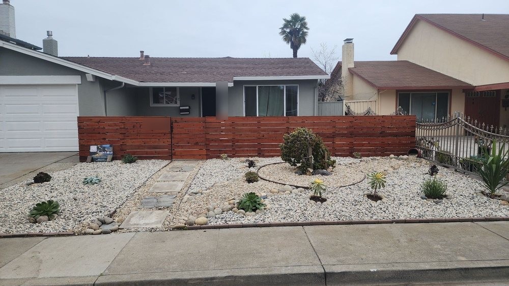 Fremont front yard with white decorative rock, succulents, a stepping-stone path and a horizontal redwood fence across the front of the house