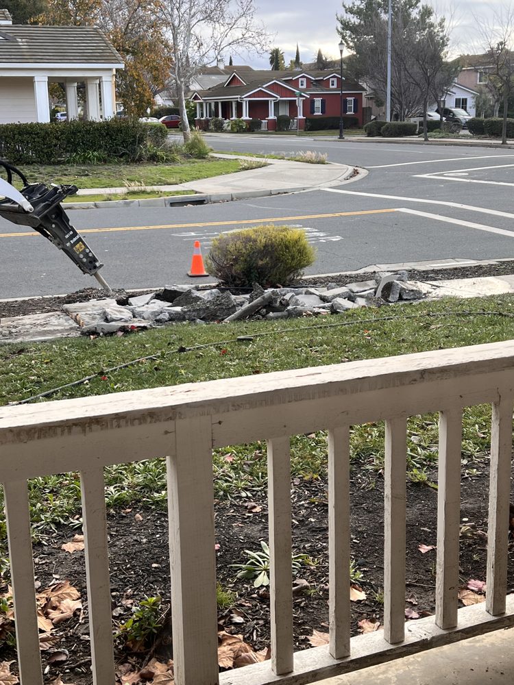 Breaker attachment removing old sidewalk concrete in front of a Pittsburg home